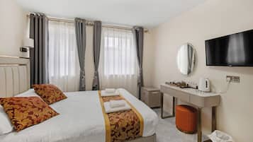 A hotel room with a bed, a desk, a TV, and a mirror.