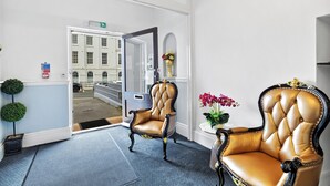 Un hall d’hôtel avec deux fauteuils en cuir, un miroir et une plante en pot.