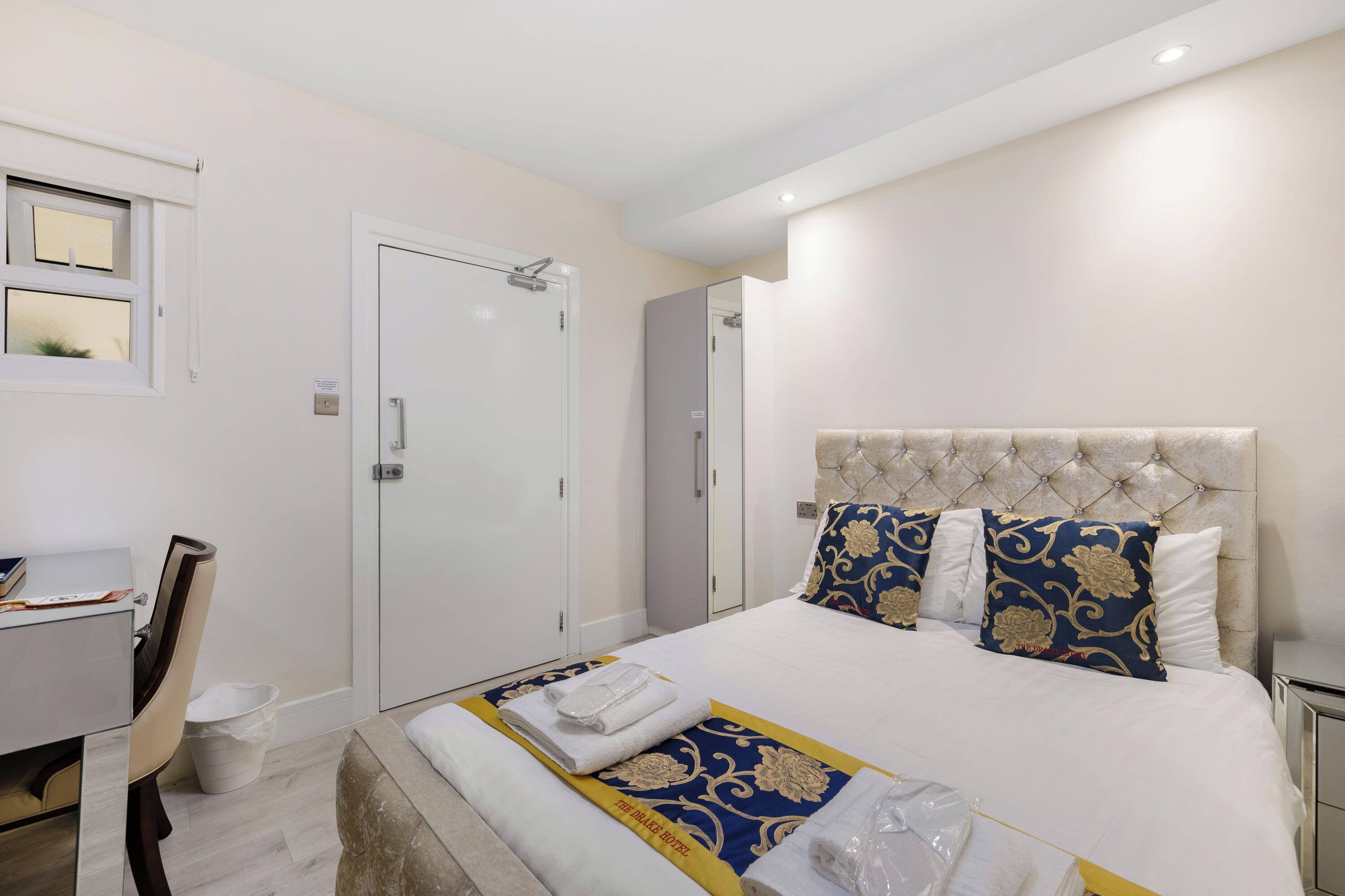Een hotelkamer met een bed, een bureau, een stoel en een kledingkast.