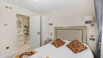 A hotel room with a bed, a nightstand, a lamp, and a bathroom visible through an open door.
