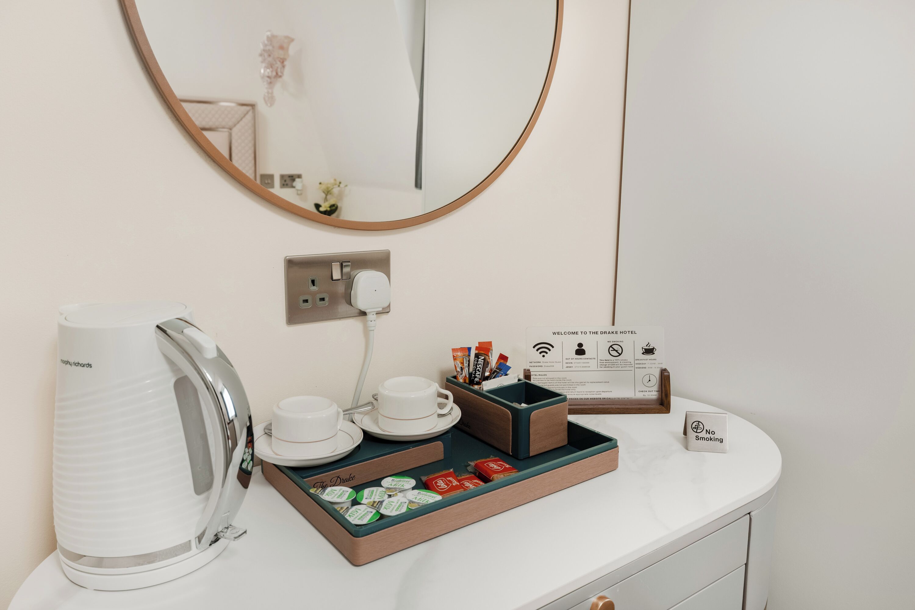 A hotel room with a white coffee station including a kettle, cups, and tea packets.