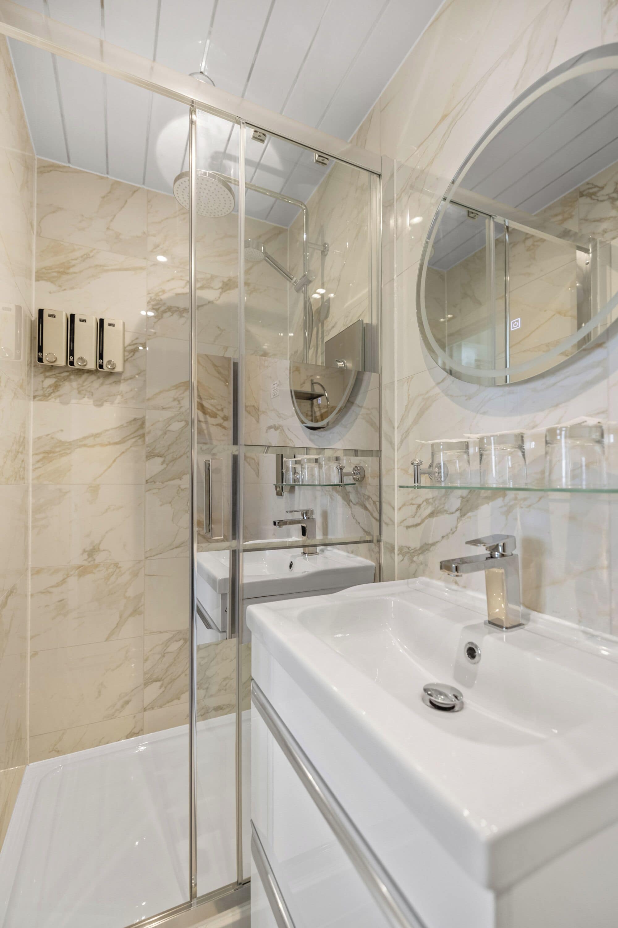 A modern bathroom with a glass-enclosed shower, a large mirror, and a white sink.