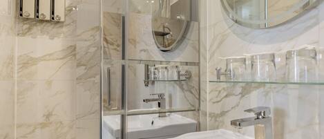 A modern bathroom with a glass-enclosed shower, a large mirror, and a white sink.