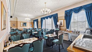 Une salle à manger d'hôtel avec plusieurs tables et chaises, un lustre et un buffet.
