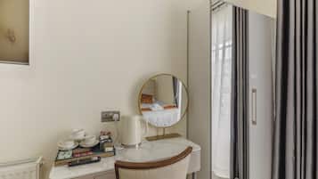 Una habitación de hotel con un escritorio de mármol, un espejo, una cama con cortinas y un armario.