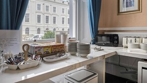 Une chambre d’hôtel dotée d’un coin cuisine avec un plan de travail en marbre, une machine à café et une vue sur un bâtiment à l’extérieur.