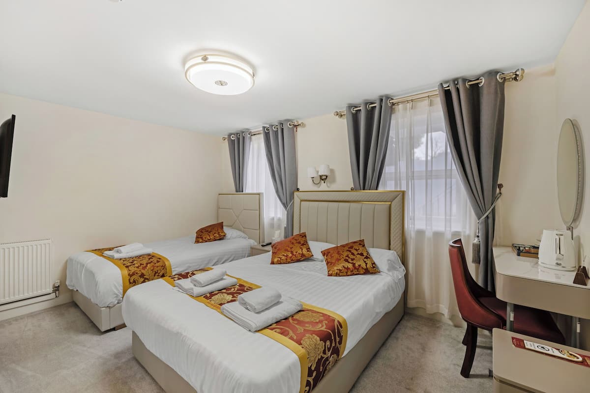 Une chambre d’hôtel avec deux lits, un bureau, une chaise, un miroir et un radiateur.