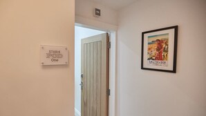 Un pasillo con una puerta identificada como 'STUDIO POD One' y un cartel enmarcado en la pared.