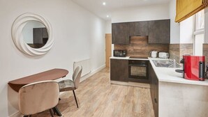Una cocina compacta con comedor, microondas, cafetera y un espejo redondo en la pared.