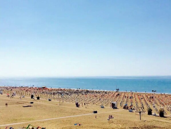 Relax on the expansive beach with rows of sunbeds and umbrellas, offering a serene ocean view.