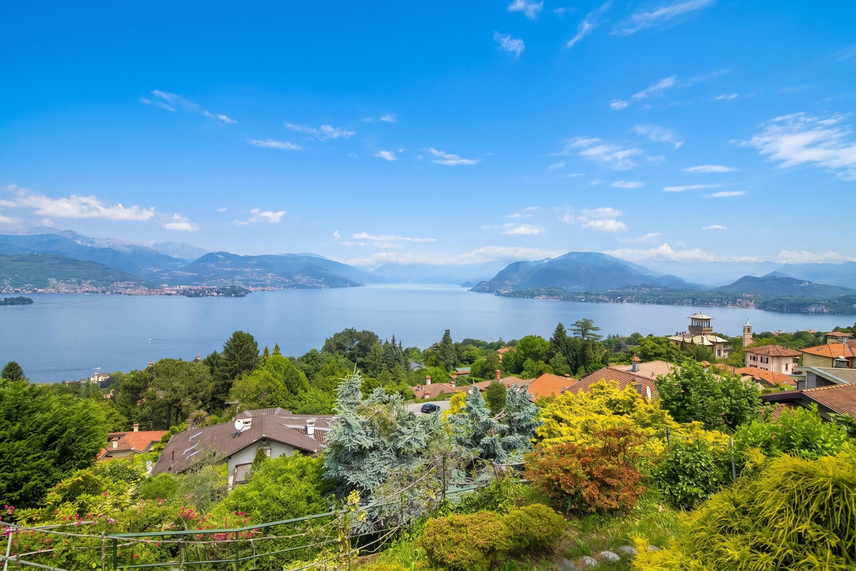 A lakeside village with houses, trees, and a clear view of the lake and mountains.