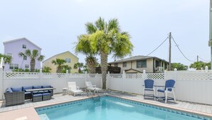 A swimming pool with lounge chairs and a table, surrounded by a white fence and palm trees. - 4 BR Beach House with a Private Pool & Steps to the Beach! Seaborn (Surfside Beach)