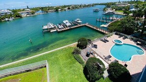 A marina with docked boats, a swimming pool, and a grassy area with lounge chairs.