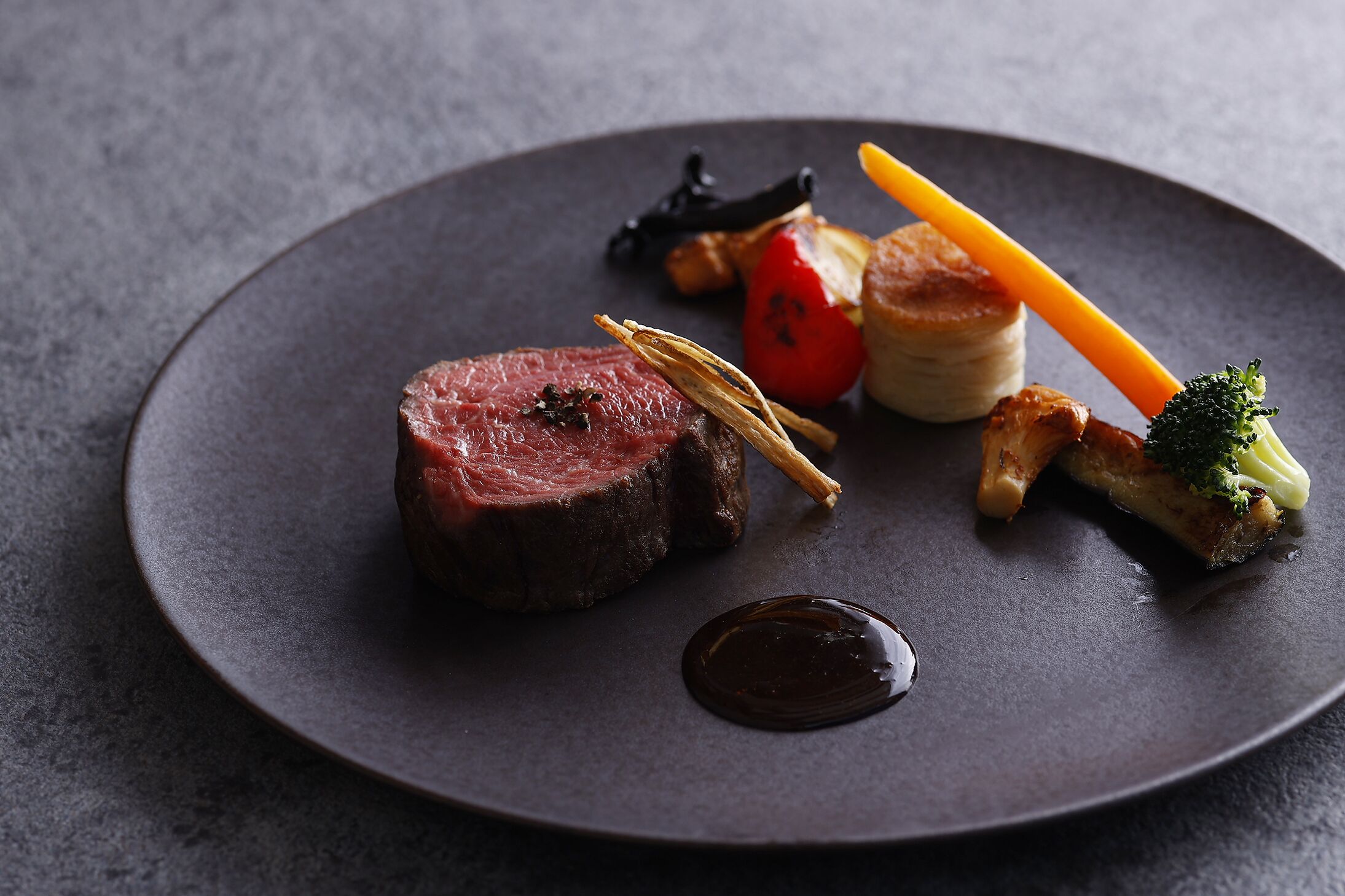 Un plato con filete, vegetales y salsa.