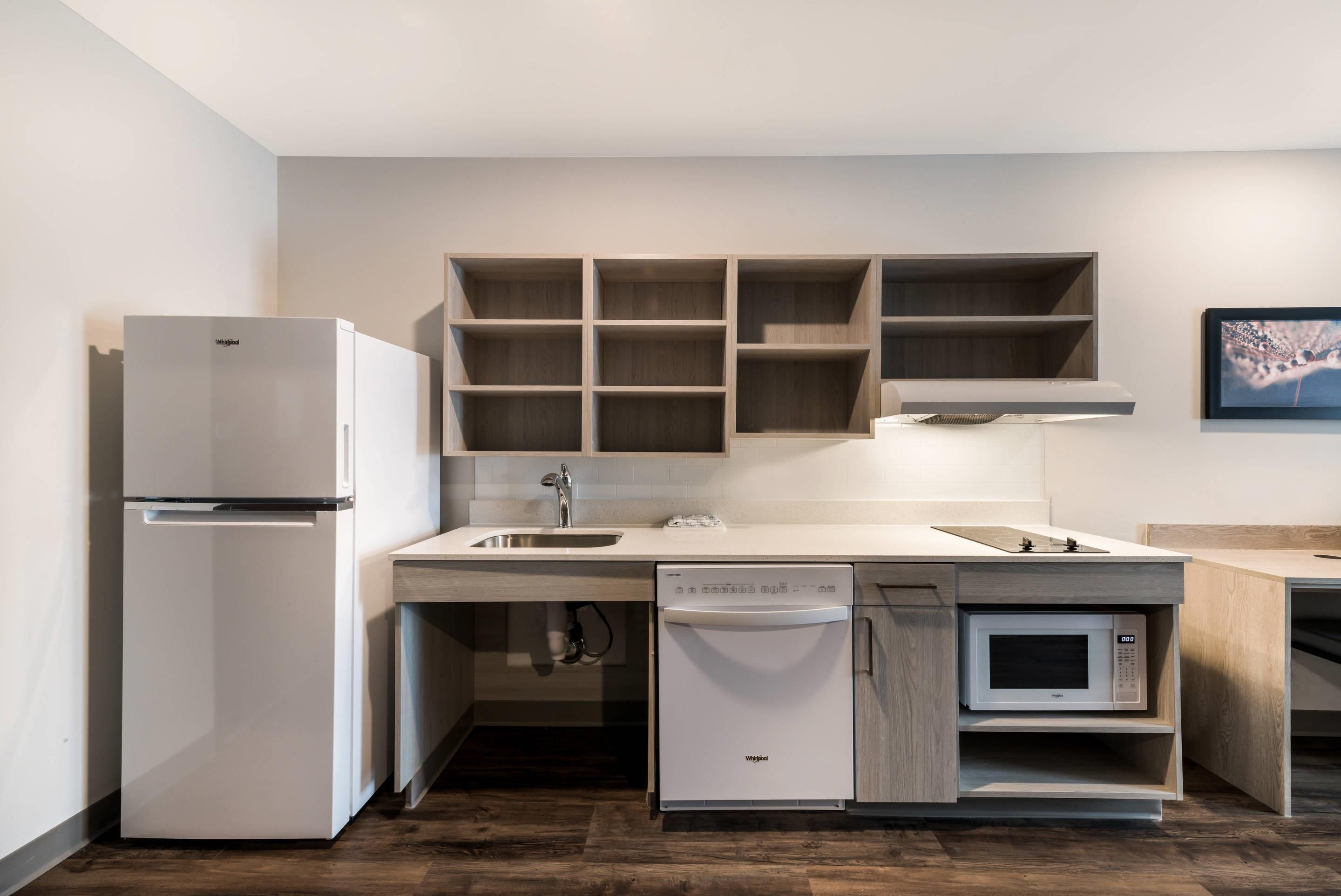 A compact kitchen with a refrigerator, dishwasher, microwave, and wooden cabinets.