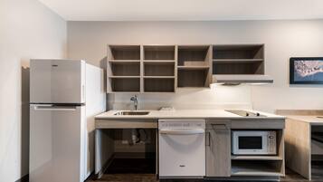 A compact kitchen with a refrigerator, dishwasher, microwave, and wooden cabinets.