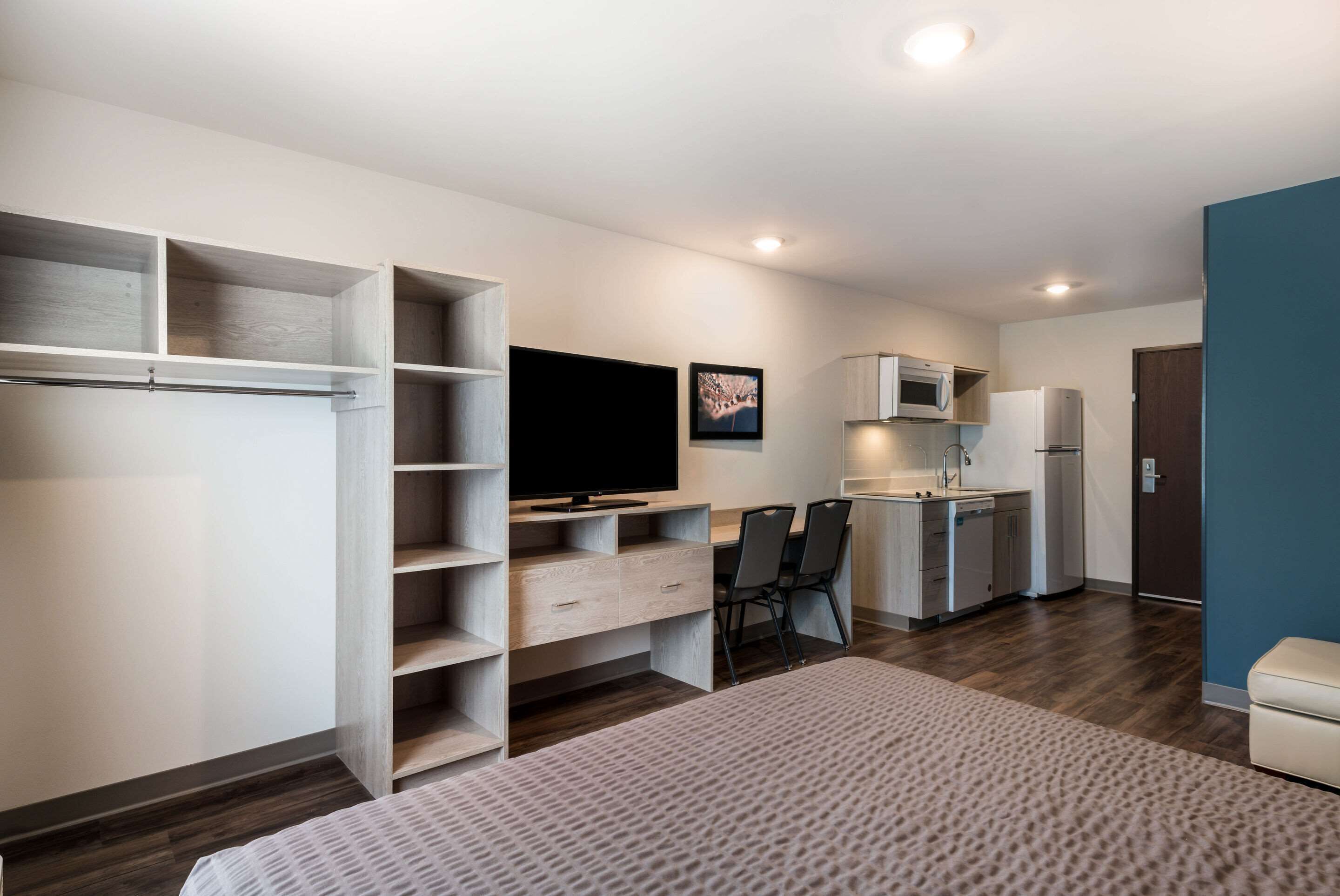 Un espacio habitable compacto con cama, televisor, kitchenette y comedor.