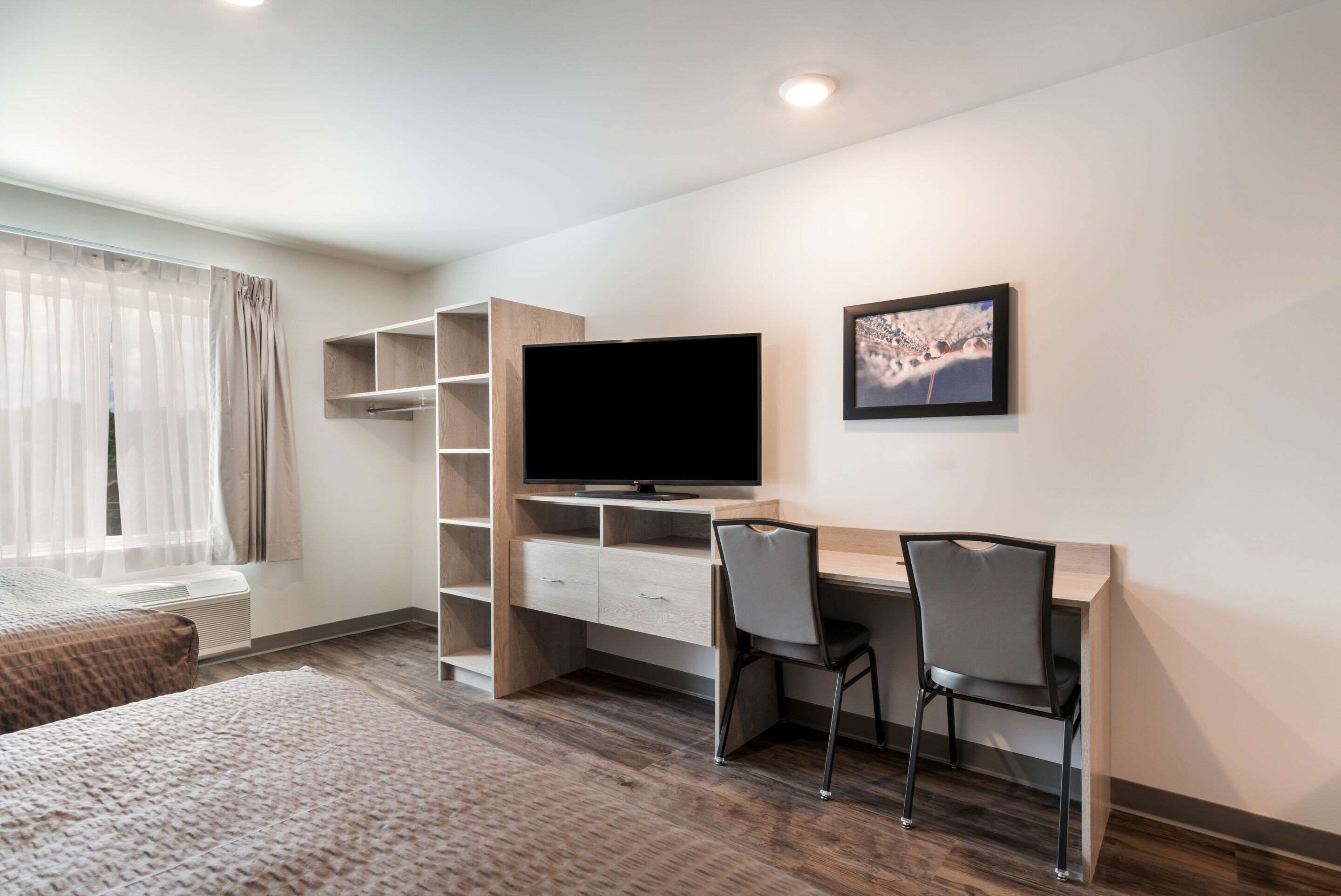 Una habitación de hotel con cama, escritorio, silla, televisor y estantería.