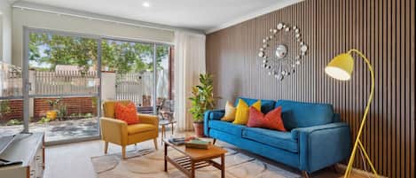A modern living room with a blue sofa, yellow armchair, and a coffee table.