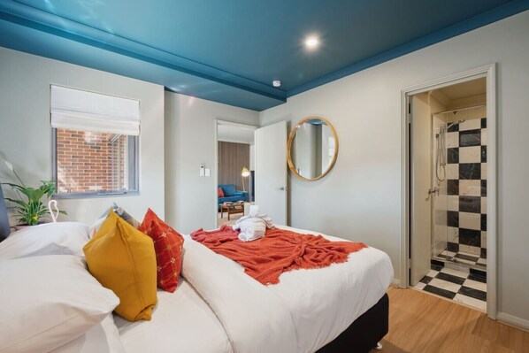 Une chambre à coucher avec un lit, une fenêtre, un miroir et un espace douche.