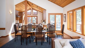 A spacious kitchen with wooden cabinets, a dining area with a glass table, and large windows allowing natural light.