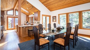 A modern kitchen with wooden beams, a central island, and large windows.