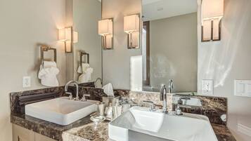 A modern bathroom with two sinks, marble countertops, and wall-mounted lighting.
