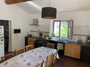 Uma cozinha com mesa de jantar, cadeiras, luminária pendente, janela e forno embutido.