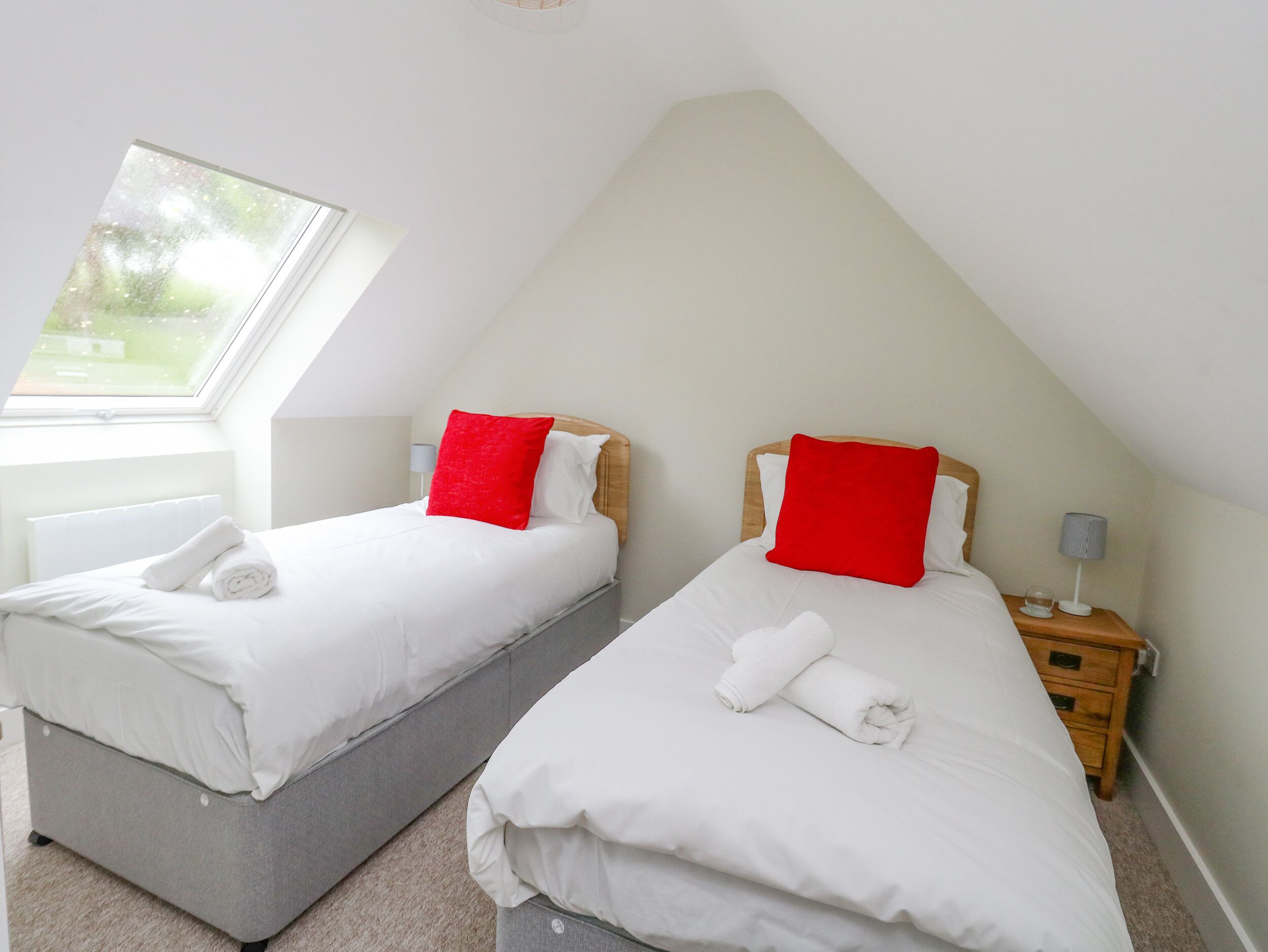 Two twin beds in a room with a sloped ceiling and a skylight.