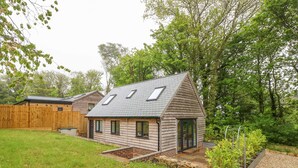 A wooden house with a sloped roof and skylights, surrounded by a grassy yard and trees. - Roman Lodge (Weymouth)