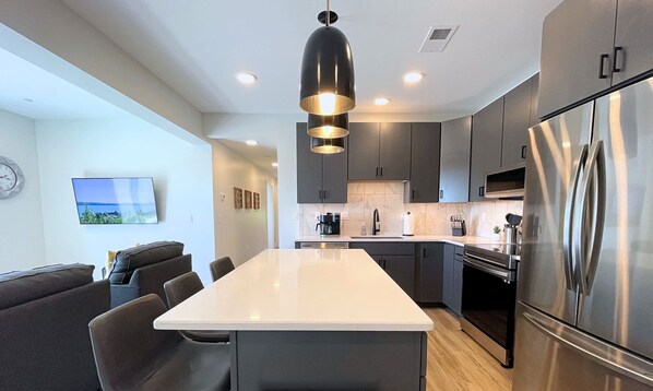 A modern kitchen with a central island, stainless steel appliances, and dark cabinetry.