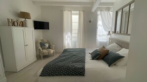 A bedroom with a bed, a chair, a TV, and a wardrobe.