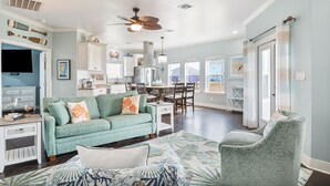 A spacious living area with a sofa, a patterned rug, and a ceiling fan.