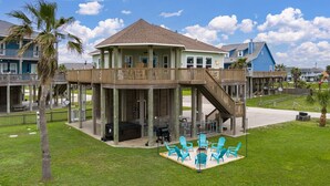 A beachfront property with a covered deck, outdoor seating, and a pool area.