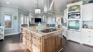 A modern kitchen with a central island, white cabinetry, and stainless steel appliances.