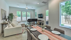 A spacious living room with a large dining table, comfortable seating, and a television.