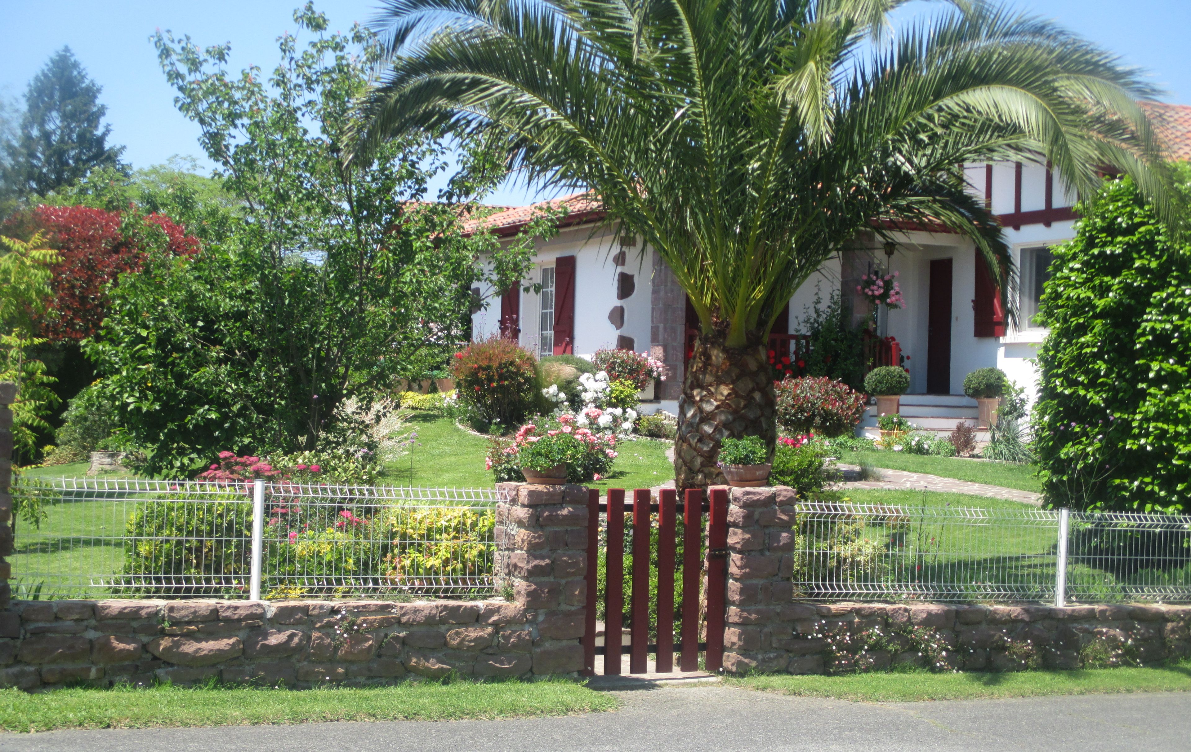 A residential property with a well-maintained garden, a stone wall, and a metal gate.