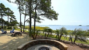 An outdoor seating area with a fire pit, picnic table, and blue chairs. - Coastal Charm at Bayside, Golf Cart Access, Pools (Selbyville)