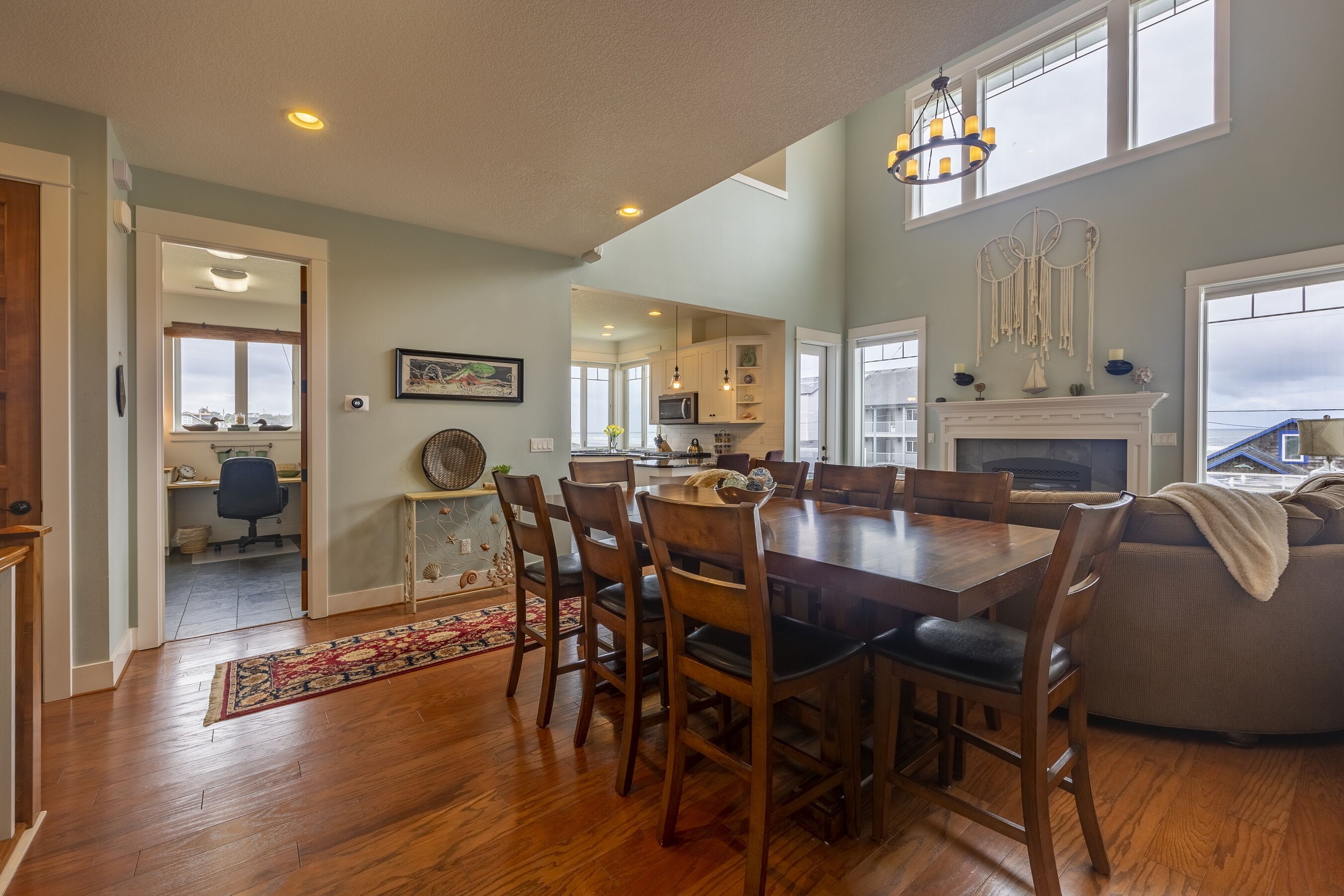 A spacious dining area with a wooden table and chairs, a fireplace, and a view of the kitchen and living room.