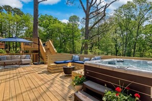 Een houten terras met een jacuzzi, zitgedeelte en een vuurkorf.