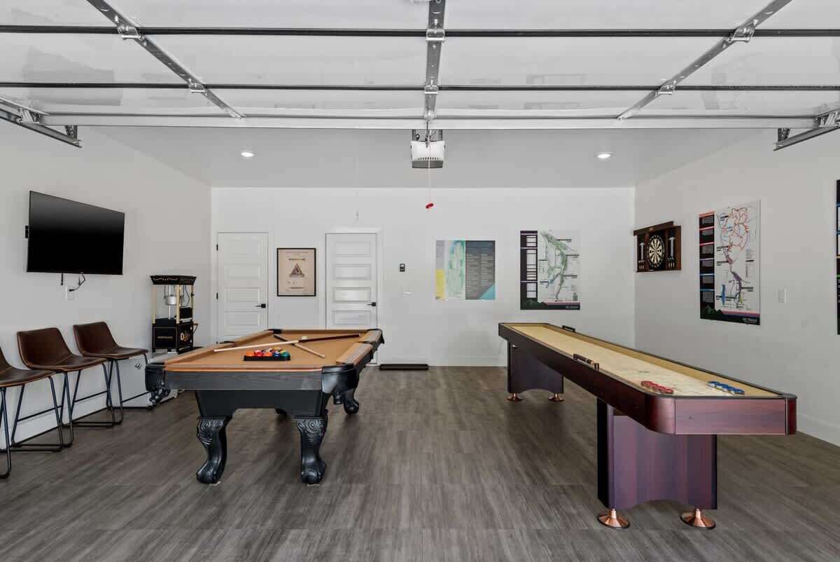 Een kamer met een pooltafel, een biljarttafel en een aan de muur bevestigde televisie.