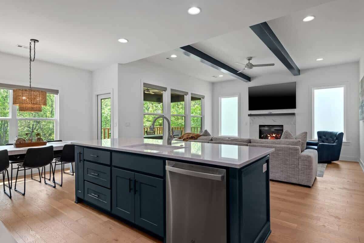 A modern kitchen with a central island, dark cabinetry, and a built-in dishwasher.