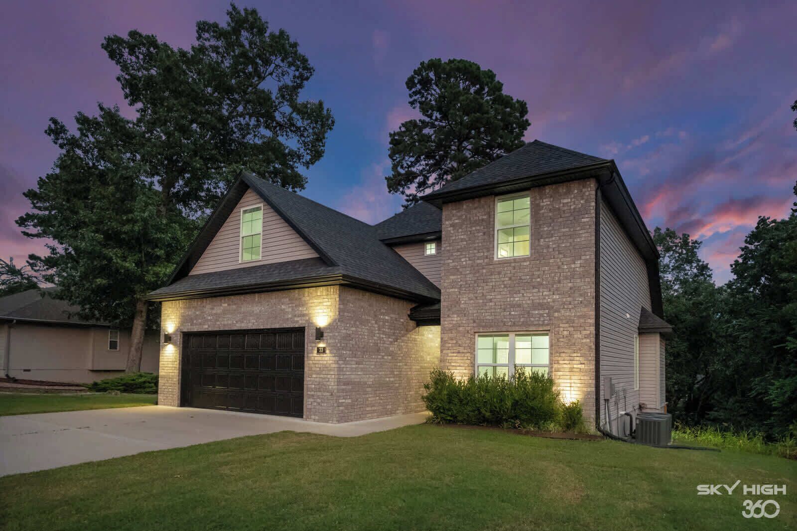 A two-story house with a garage, brick exterior, and a well-maintained lawn.