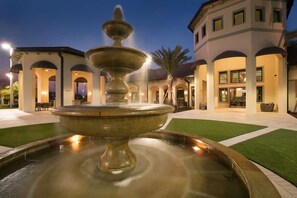 Stroll through a serene outdoor oasis surrounded by a central fountain and lush palm trees.
