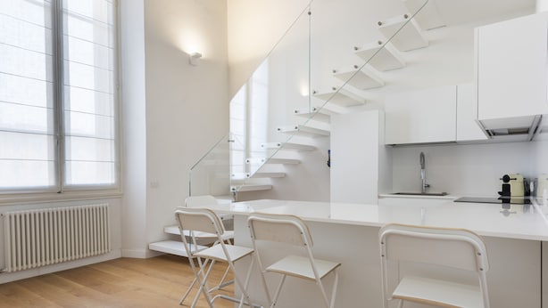 A modern kitchen with a central island, white cabinetry, and a glass staircase. - San Gallo Luxury by Mmega (Florence)