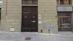 A building with a dark wooden double door, a sign reading "VIA N.GALLO", and a "HOME" sign above a barred window. - San Gallo Luxury by Mmega (Florence)