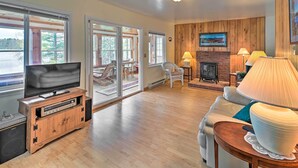A spacious living room with a television, wooden entertainment unit, and a fireplace. - Lakefront Broadalbin Getaway w/ Deck + Kayaks (Broadalbin)