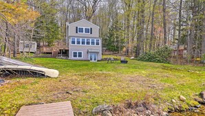 A two-story house with a deck, surrounded by trees and a small stream. - Lakefront Broadalbin Getaway w/ Deck + Kayaks (Broadalbin)