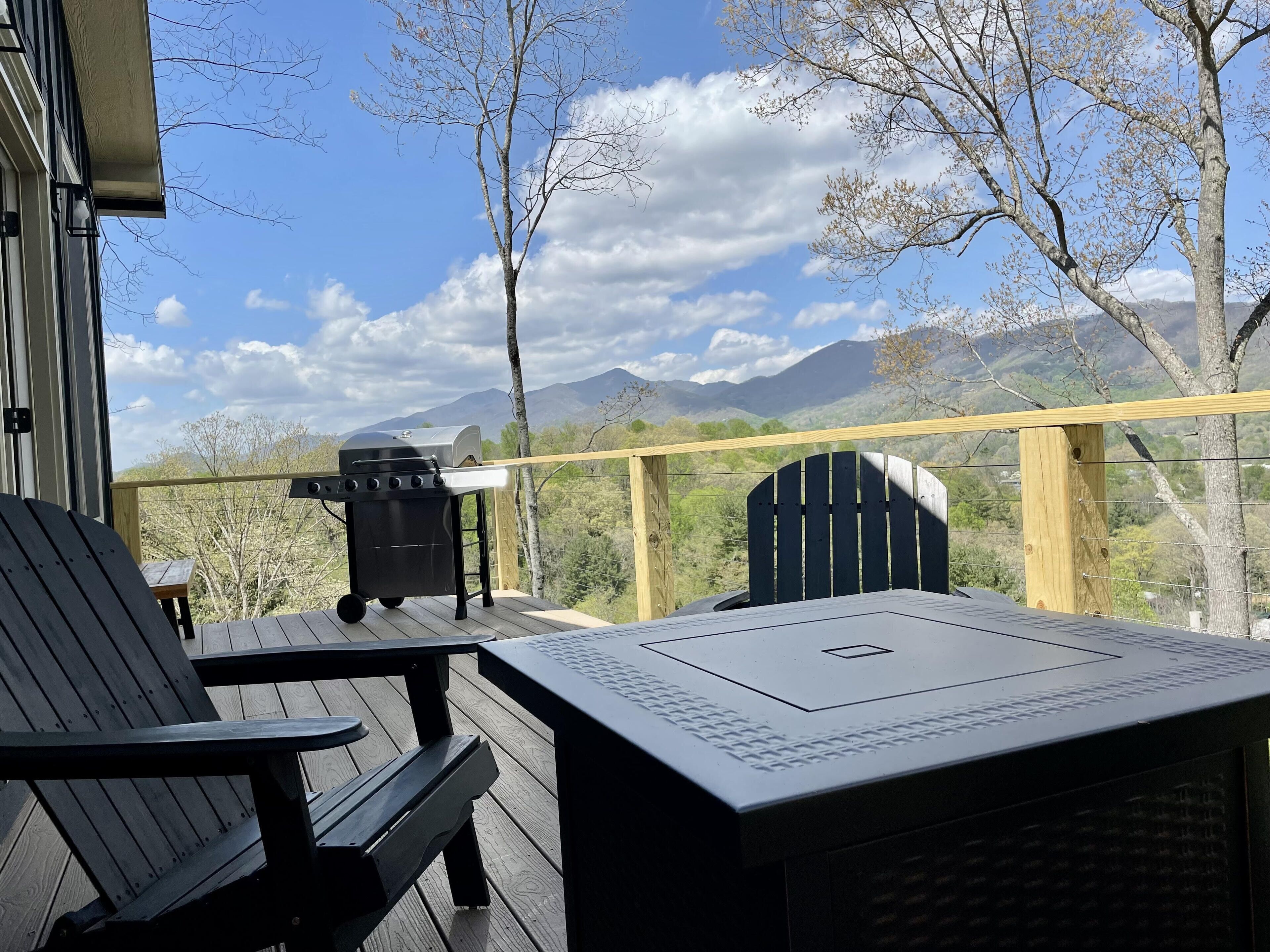 Une terrasse avec une table et des chaises, un barbecue et une vue sur les montagnes.