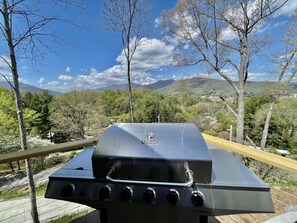 Ein Char-Broil Grill mit vier Brennern, vor einer Berglandschaft und blauem Himmel.